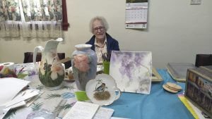 Mrs Sylvia Dadd with all the work that she has completed as part of the Condobolin China Painting Club in the last 12 months. Image Credit: Lynette McCumstie.