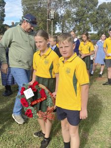 Students holding a wreath that was placed at the memorial on behalf of the school. 