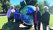 Roz Bennett, Pam Brewer, Claire Devaney and Tove Larsen pointing at Malaysia on a large globe.